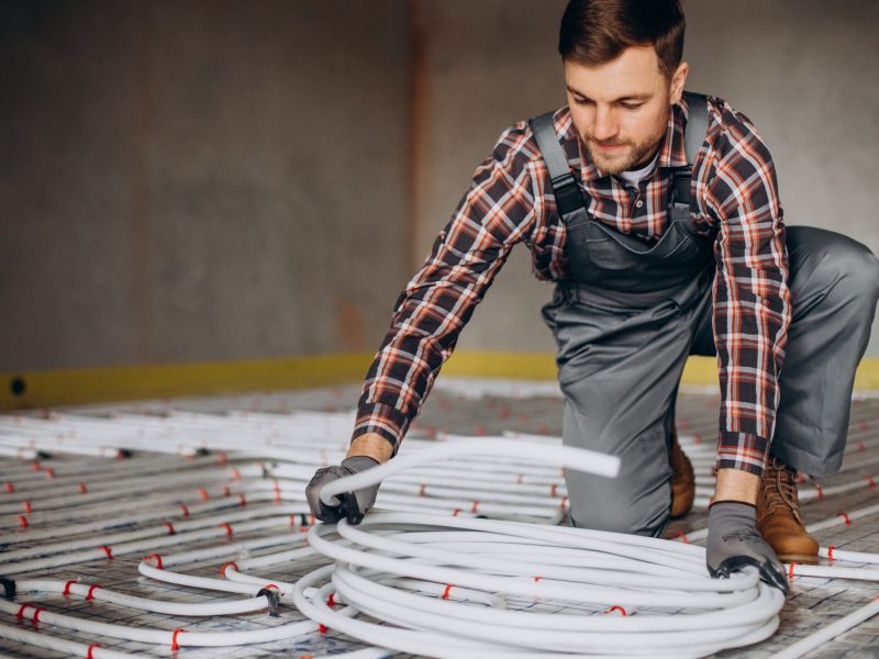 Service man instelling house heating system under the floor
